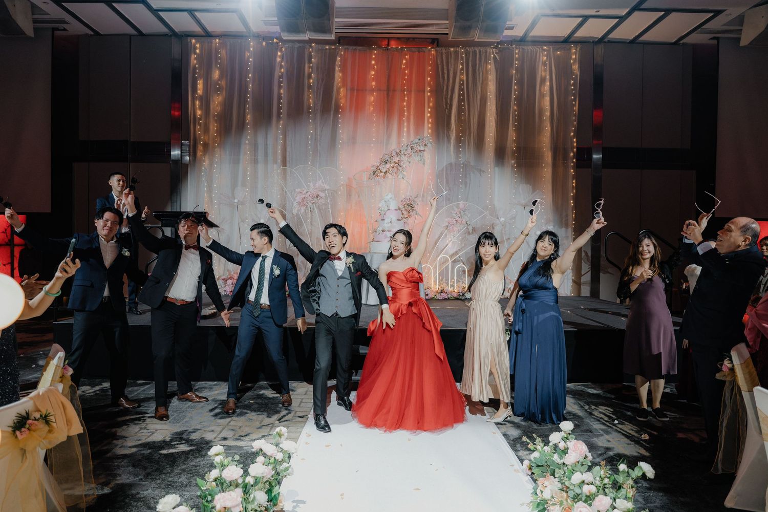 Festive wedding celebration in a modern venue with decorative white curtains and elegant lighting.