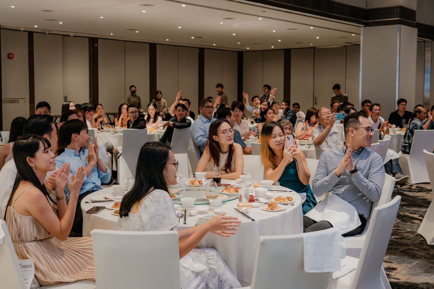 Wedding guests seated at long tables during indoor reception celebration.