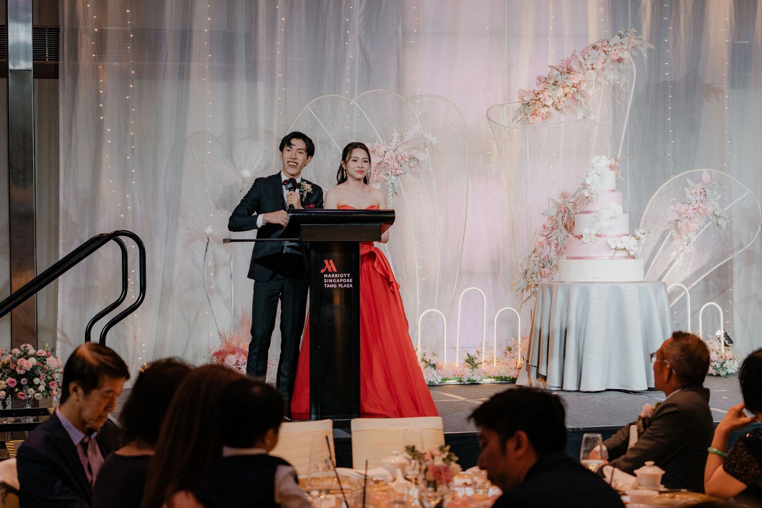 Elegant wedding reception setup with white draping and floral arrangements.