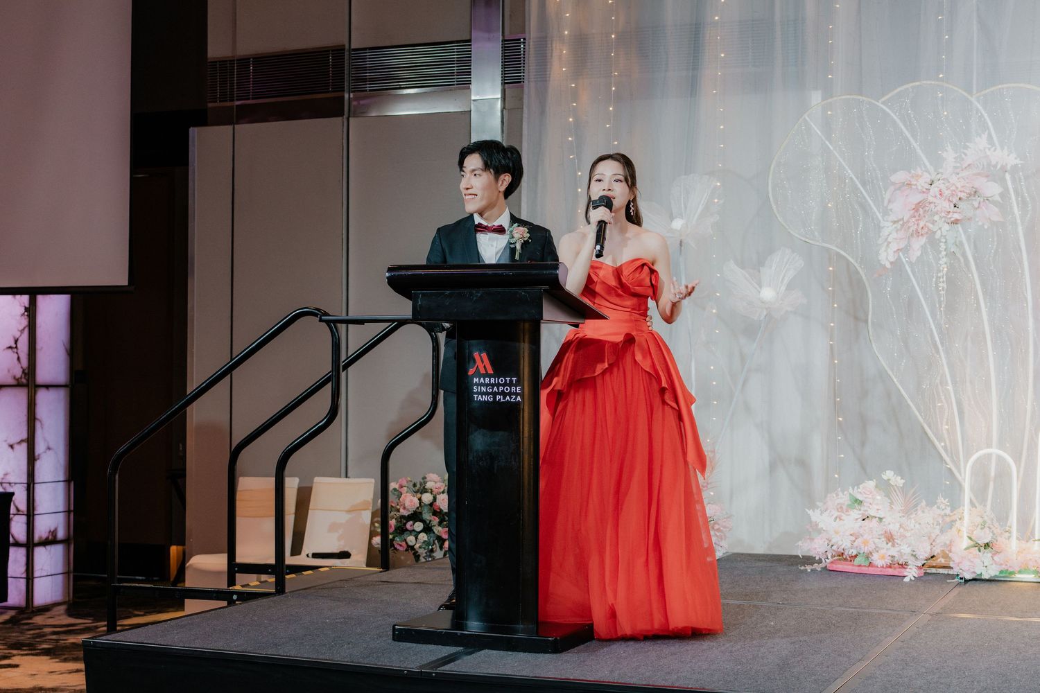 Elegant ballroom stage decorated with soft lighting and flowing curtains for a wedding celebration.