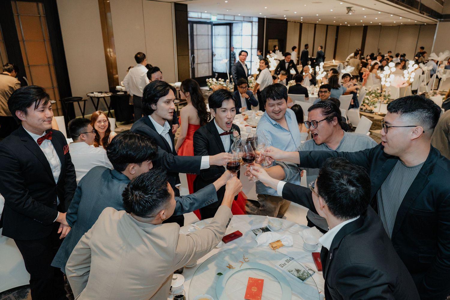 Crowded wedding reception with guests mingling in formal attire.