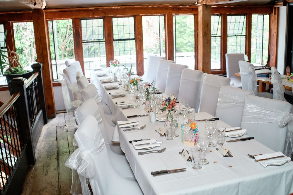 Elegant white table setting at a rustic restaurant with wooden windows and natural lighting creates an intimate dining ambiance.