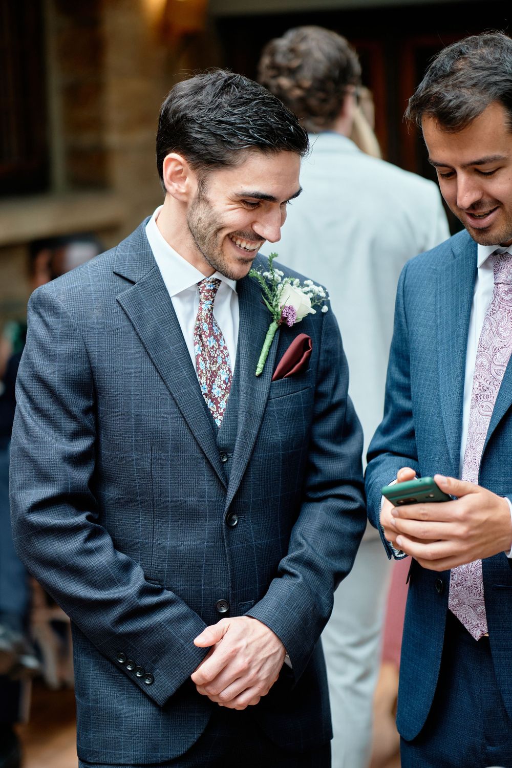 A sequence of photos showing two men in formal suits looking at something on a mobile phone and sharing a laugh.