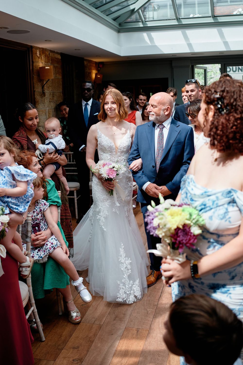 Wedding celebration sequence showing guests dancing and socializing in a venue with skylights and hardwood floors.