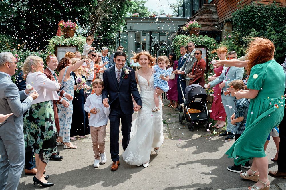 A large group of wedding guests celebrates by dancing together in a line formation outdoors during a reception.