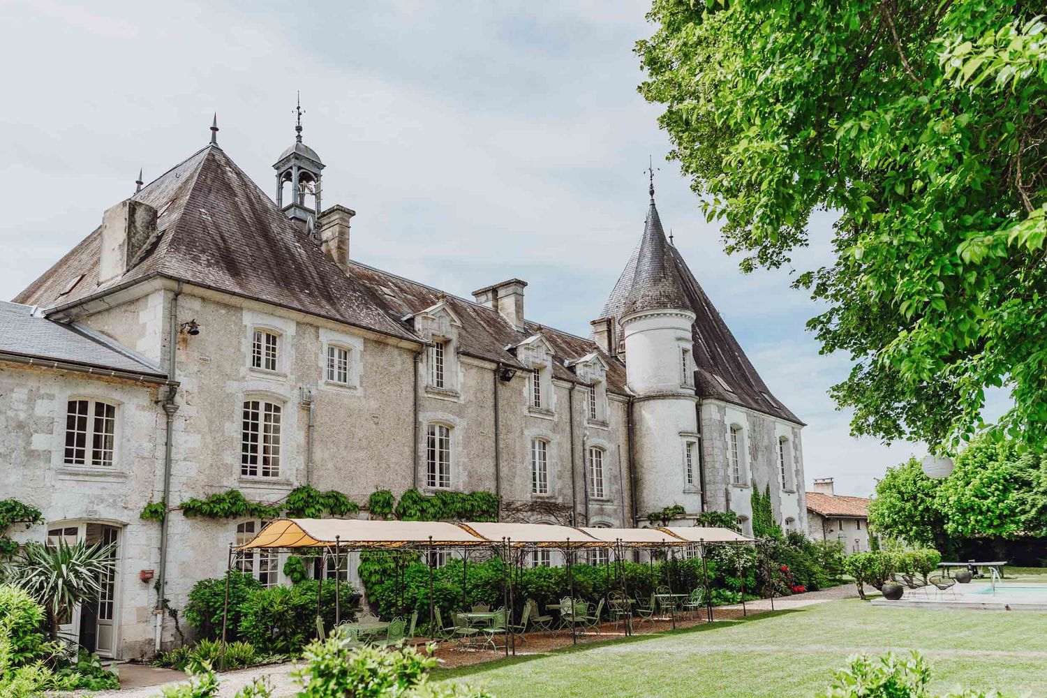 A grand French chateau with elegant architecture, turrets and manicured gardens set against an overcast sky.