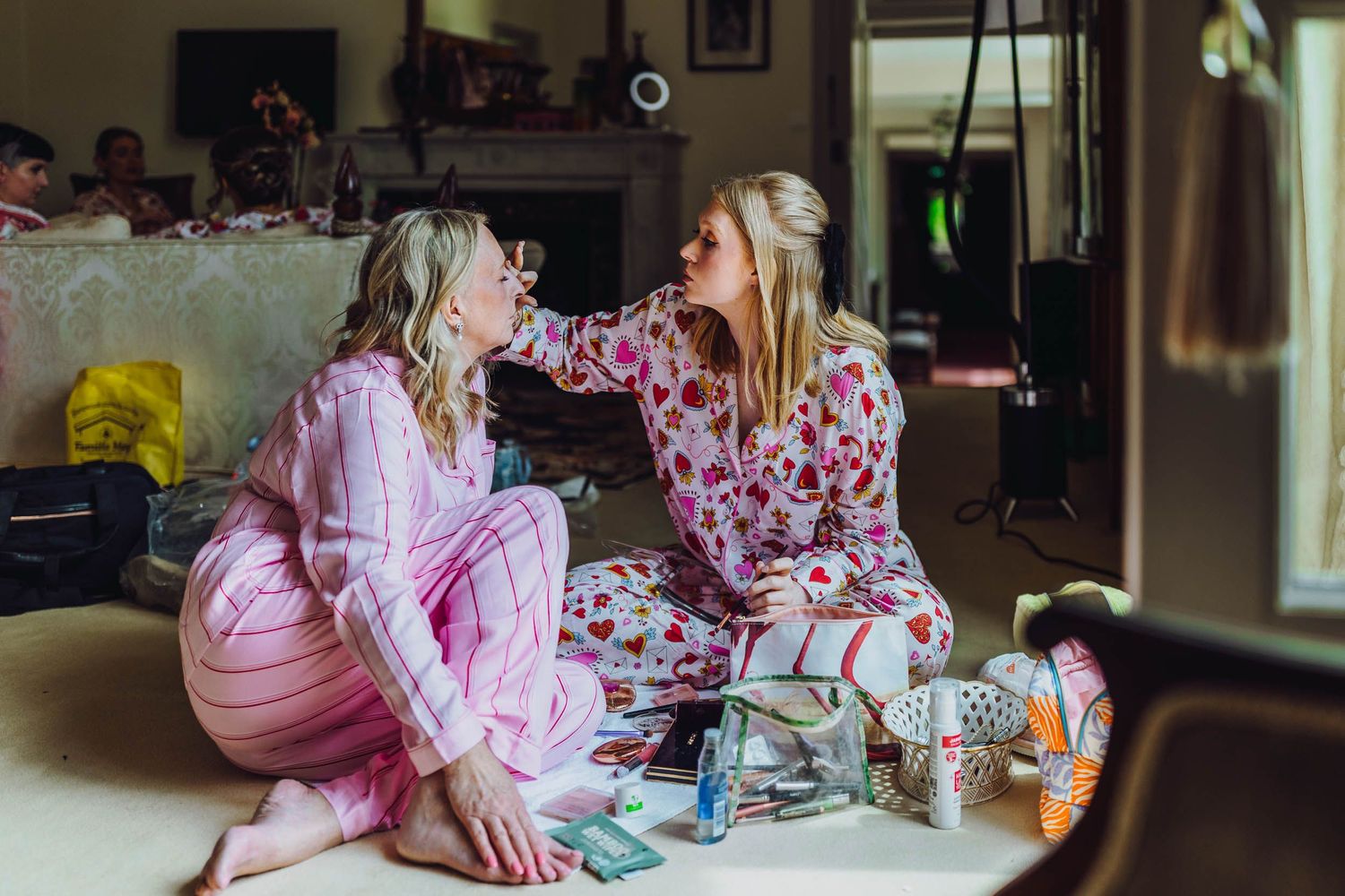 People in pink pajamas share animated conversations at a tea party gathering spread across a long table.