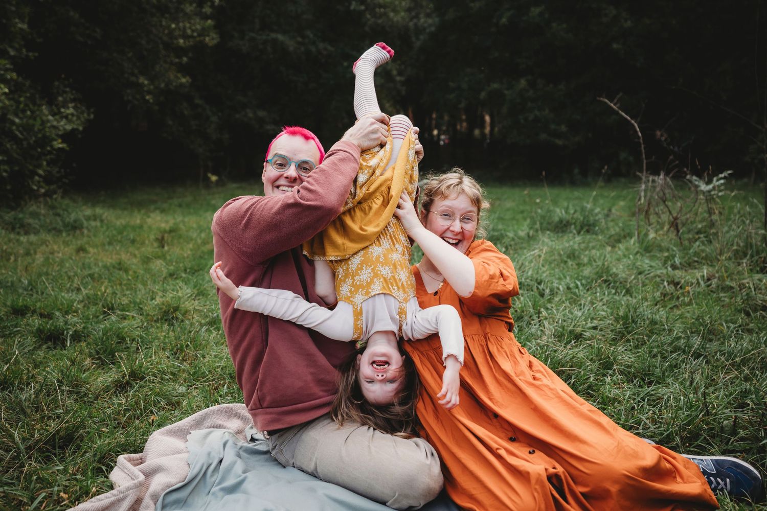 A joyful group huddle together on grass during an outdoor gathering.