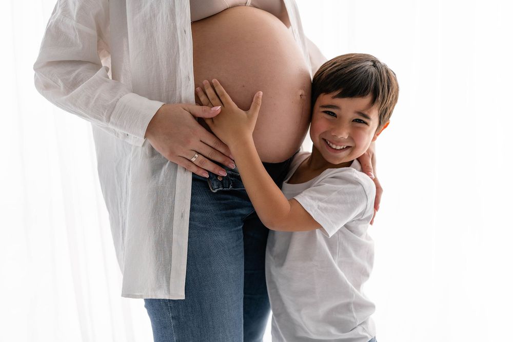 A touching moment of a young child hugging a pregnant belly.