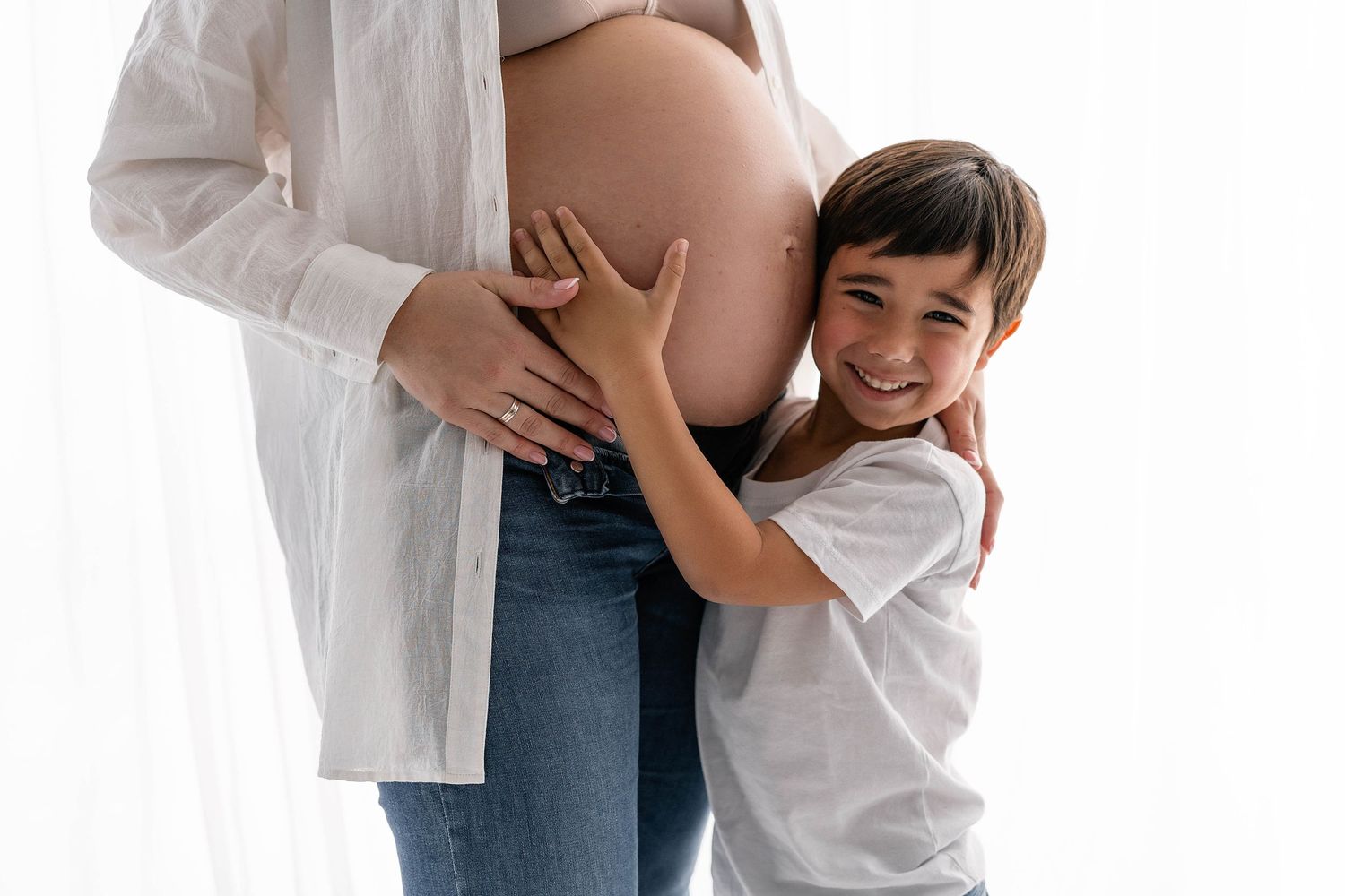 A touching moment of a young child hugging a pregnant belly.