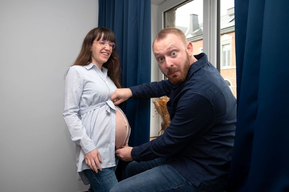À Saint-Hubert, couple photographié à domicile lors d’une séance photo de grossesse avec une pose humoristique