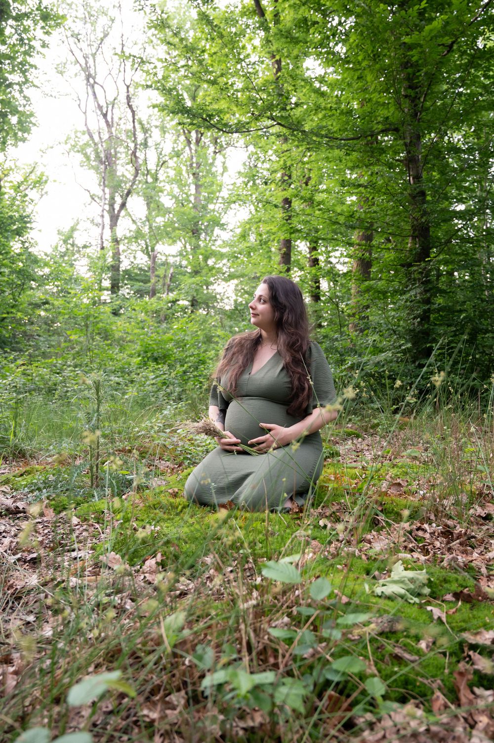 Femme enceinte assise en forêt à Barvaux lors d’une séance photo grossesse en lumière naturelle