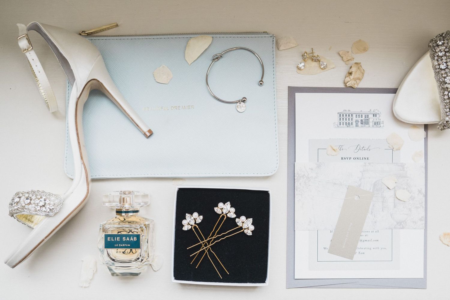 Wedding accessories including white heels, perfume bottle and invitation card arranged on light blue surface at The Westin Nova Scotian, NS.