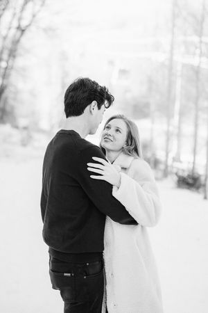 A romantic black and white winter engagement photo sequence shows a couple embracing in the snow.