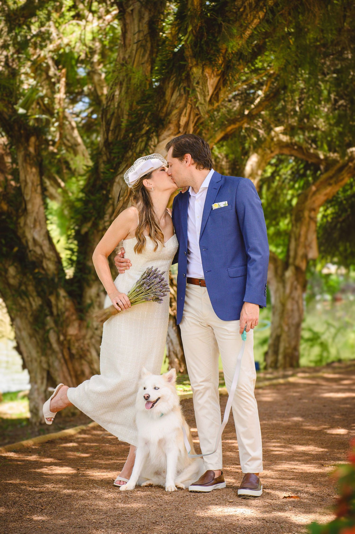 A bride and groom dancing and celebrating at their reception with bouquet and blue suit attire.