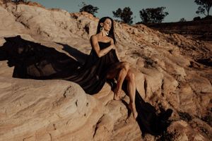 Artistic fashion photograph on textured rock formation during golden hour.