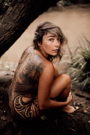 Artistic portrait showcasing intricate tribal tattoo design in natural outdoor setting.