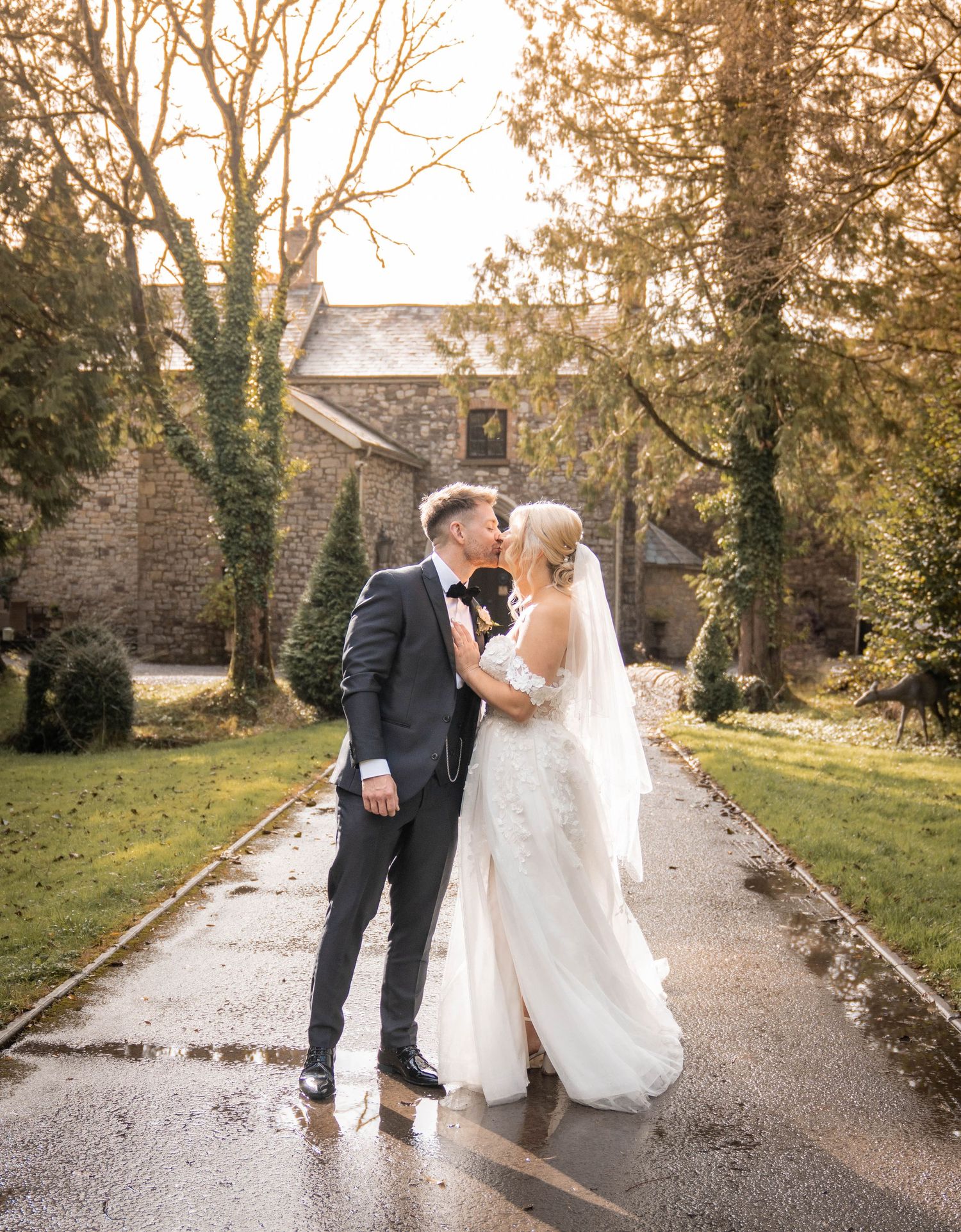 Wedding couple walking and dancing together on a rain-soaked pathway surrounded by autumn trees.