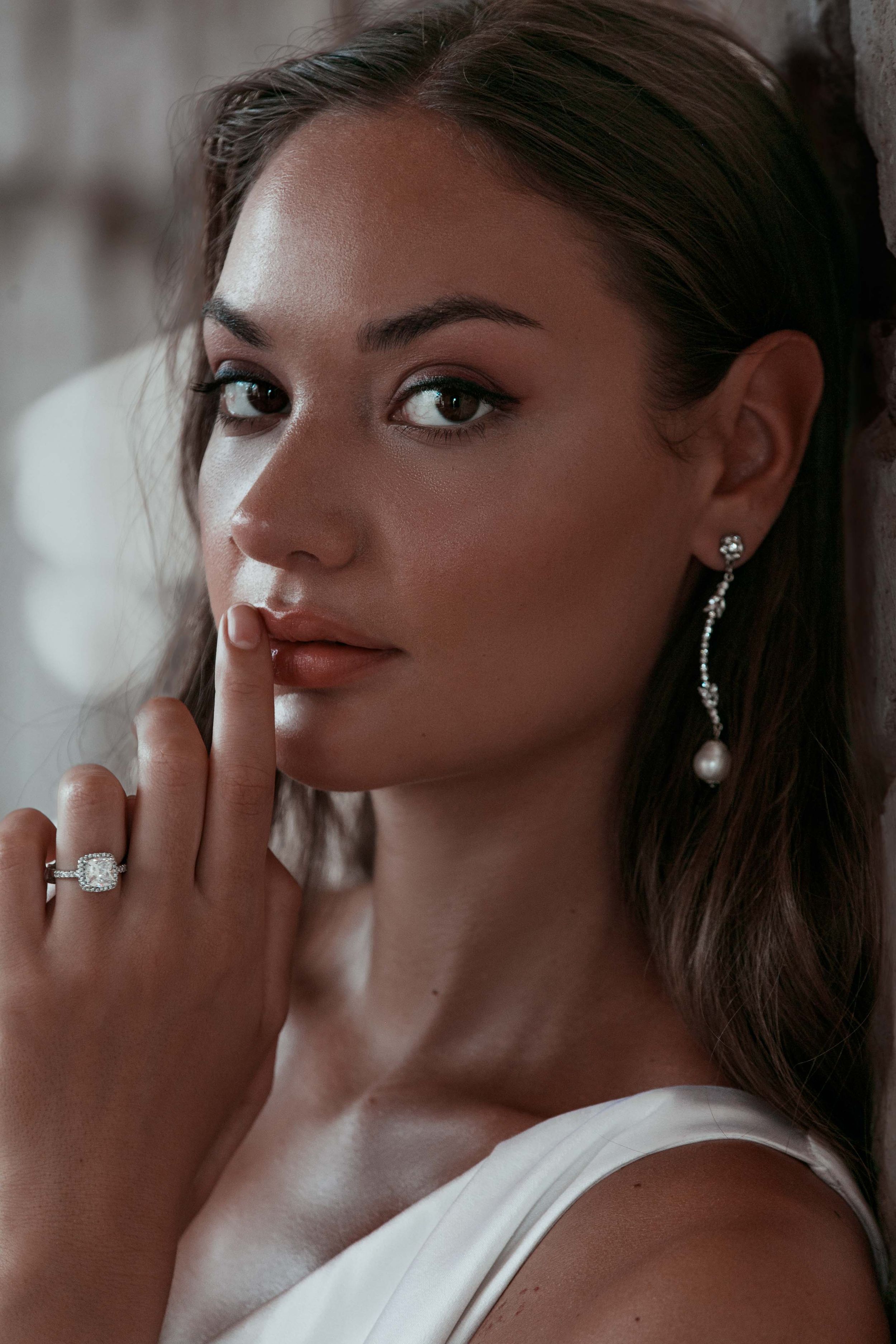 Beautiful bridal portrait with elegant jewelry featuring a white dress, statement earrings and an engagement ring.