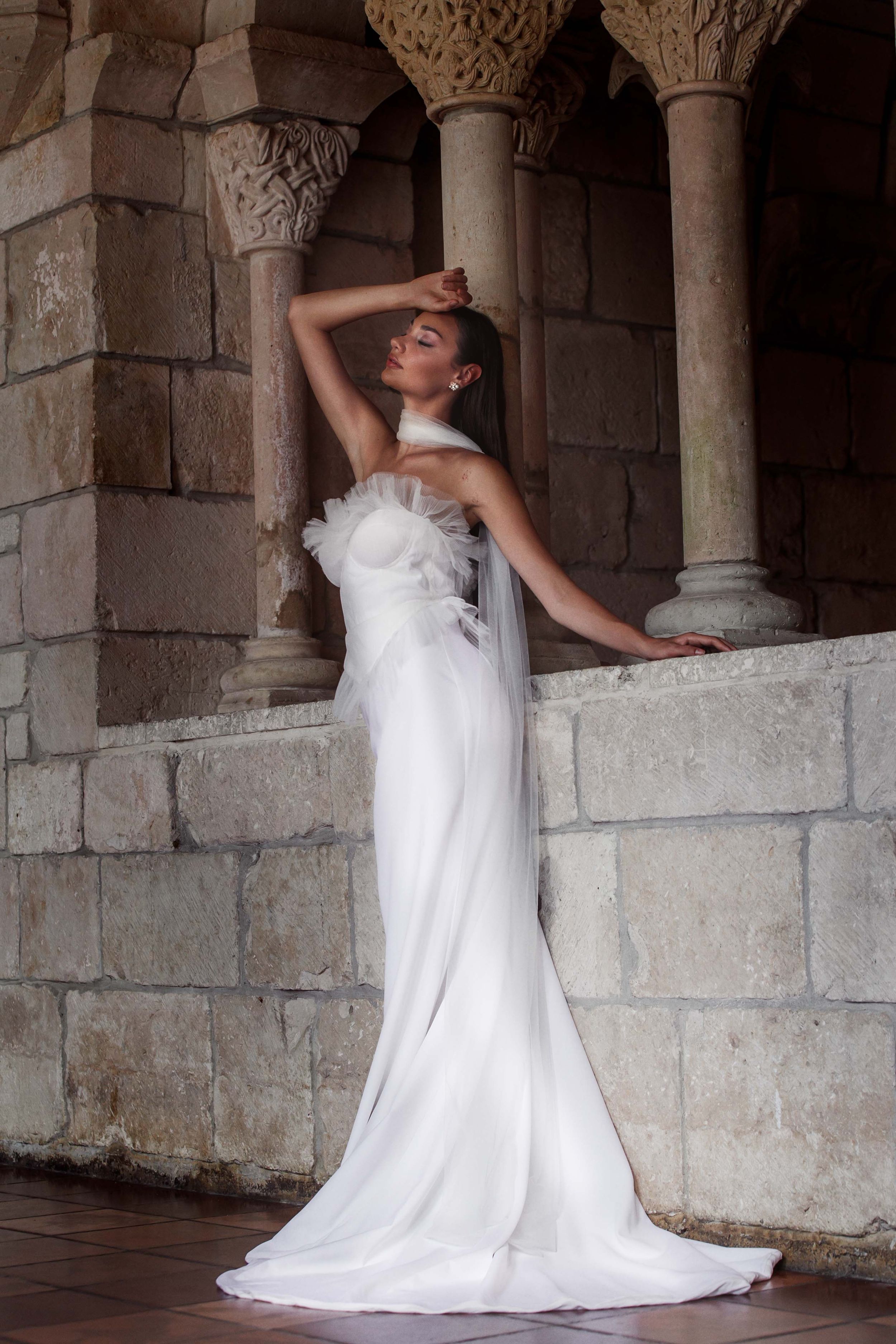 Multiple photos show a bride in a flowing white wedding dress posing gracefully against stone archways and columns.