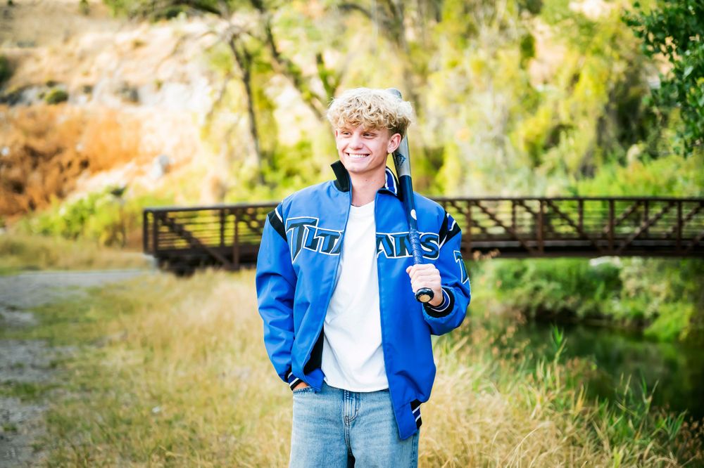 Student wearing bright blue varsity jacket standing on bridge path.