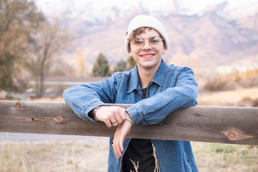 Casual winter portrait with denim jacket and knit beanie against mountain backdrop.