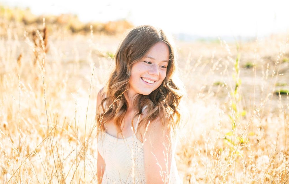 Sunlit profile portrait in golden wheat field with natural backlighting and soft warm tones.
