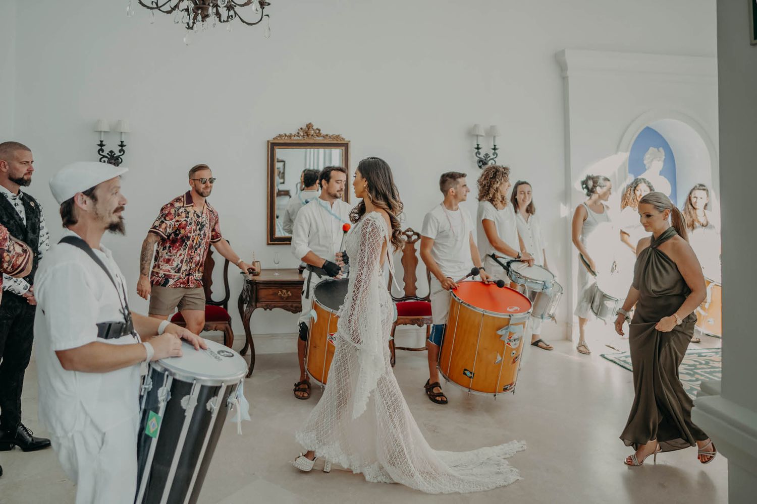 Musicians playing drums and percussion instruments perform during a celebration in an elegant white indoor venue.