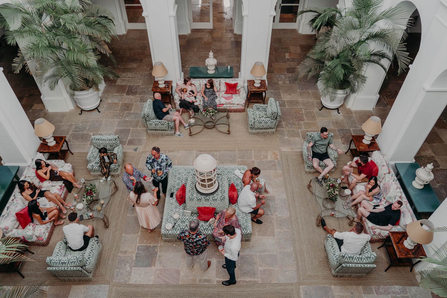 An overhead view of a wedding reception with guests gathered around tables in an ornate courtyard setting.