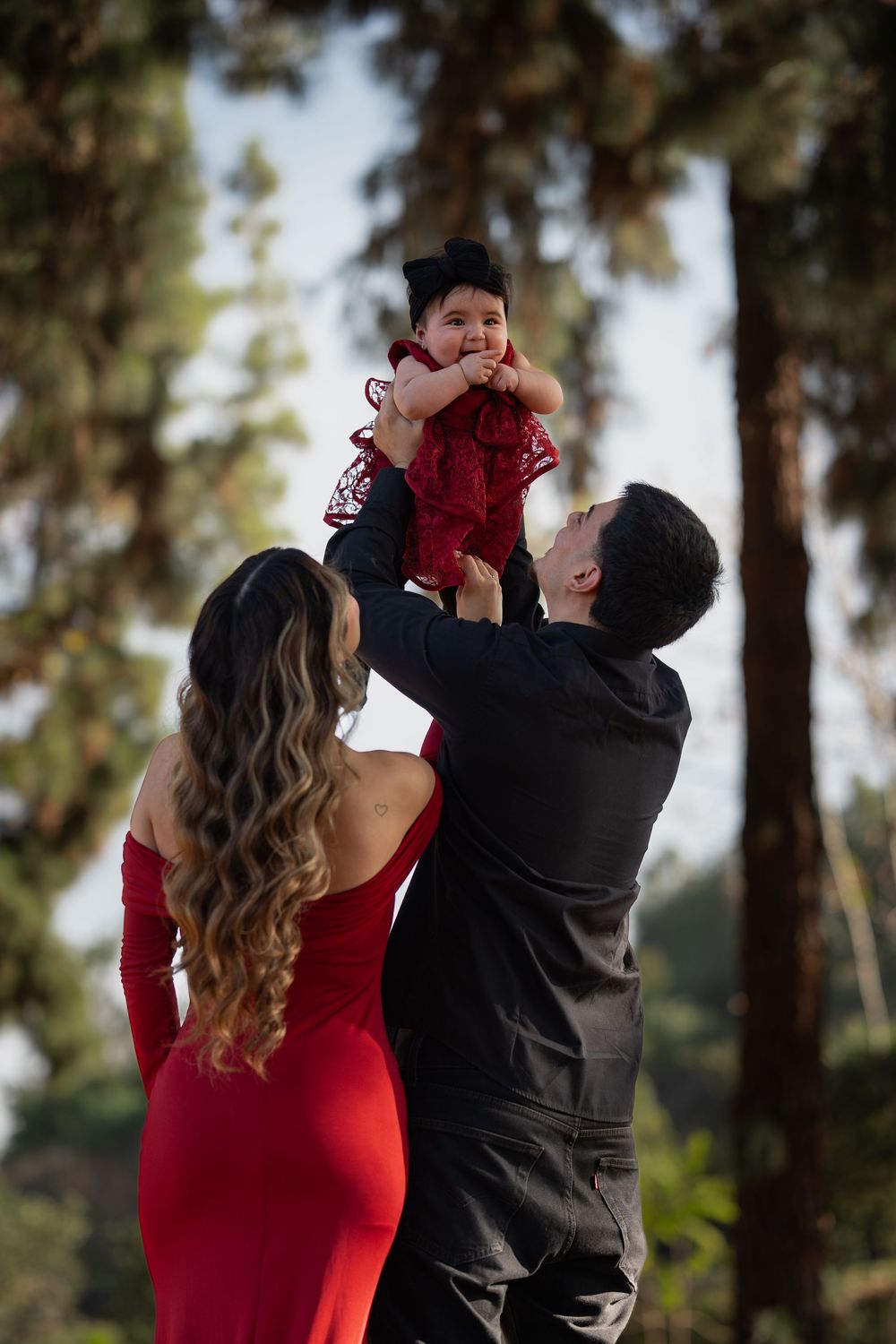 A couple in formal attire dances together outdoors, with the person in red being gracefully dipped during their dance.