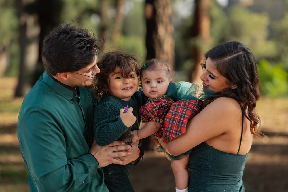 A family embraces in a forest setting during an outdoor photo session at sunset.
