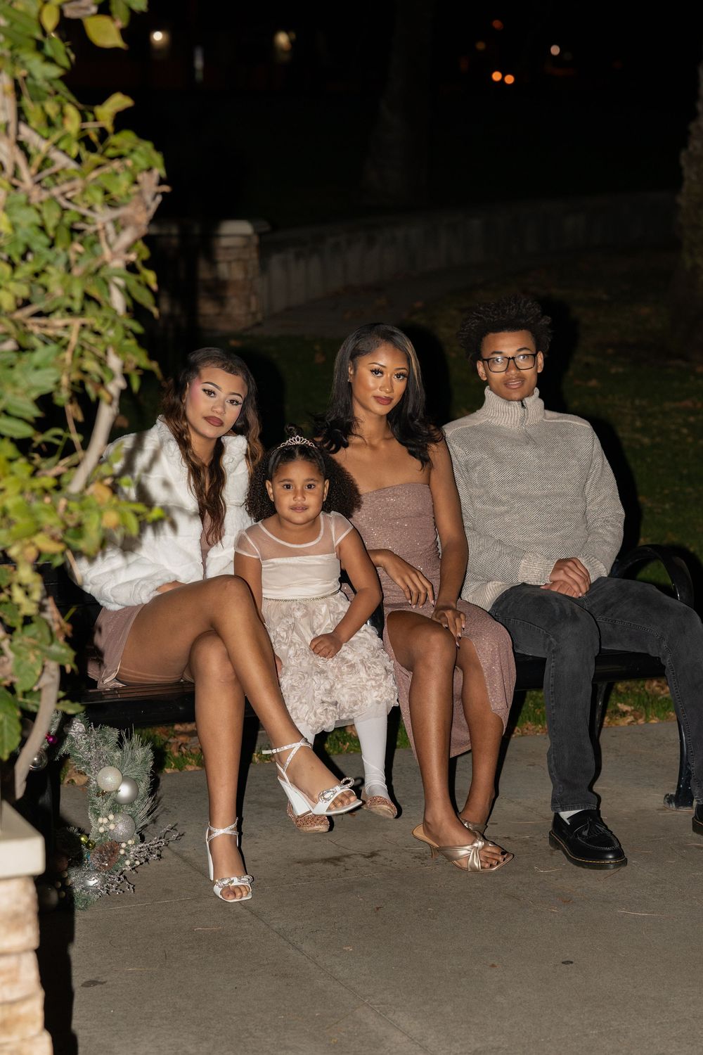 People sitting together outdoors at night wearing formal attire and white dresses.
