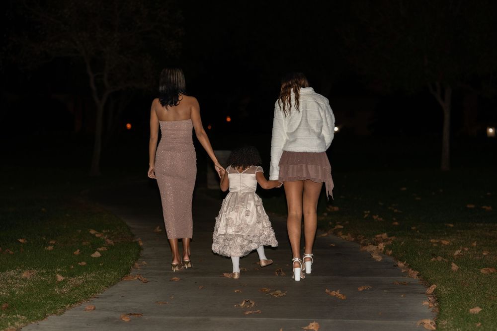 People walking together on a dark path at night through fallen autumn leaves.