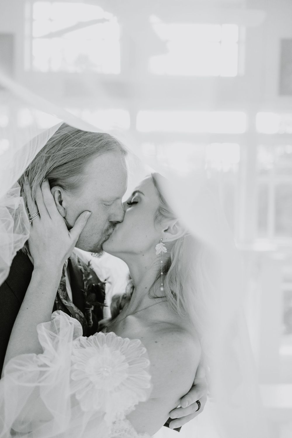 Intimate wedding couple moment captured in ethereal white light.