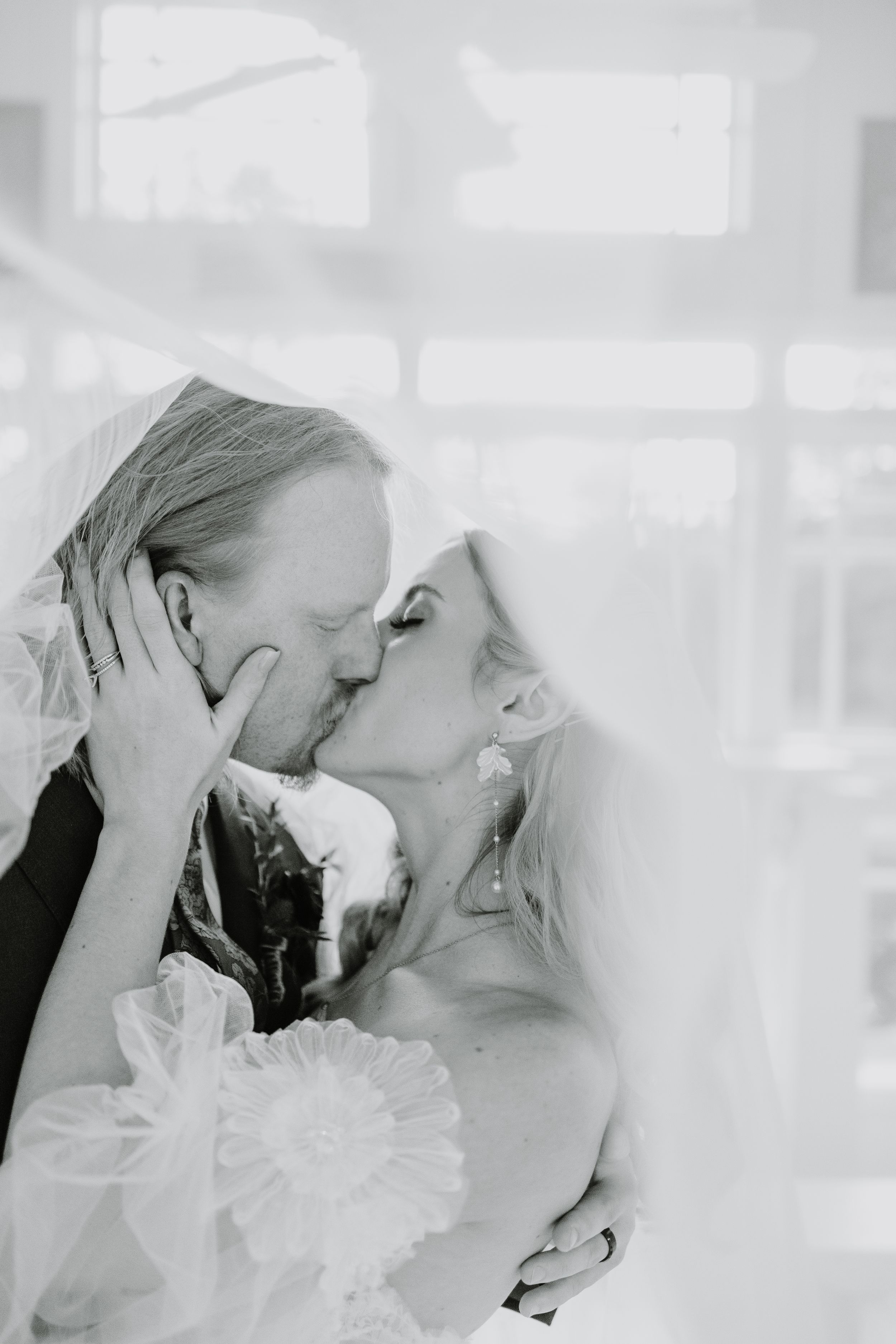 Intimate wedding couple moment captured in ethereal white light.