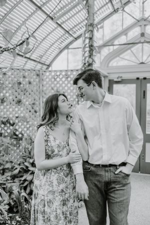 Playful engagement session in greenhouse with floral backdrop.
