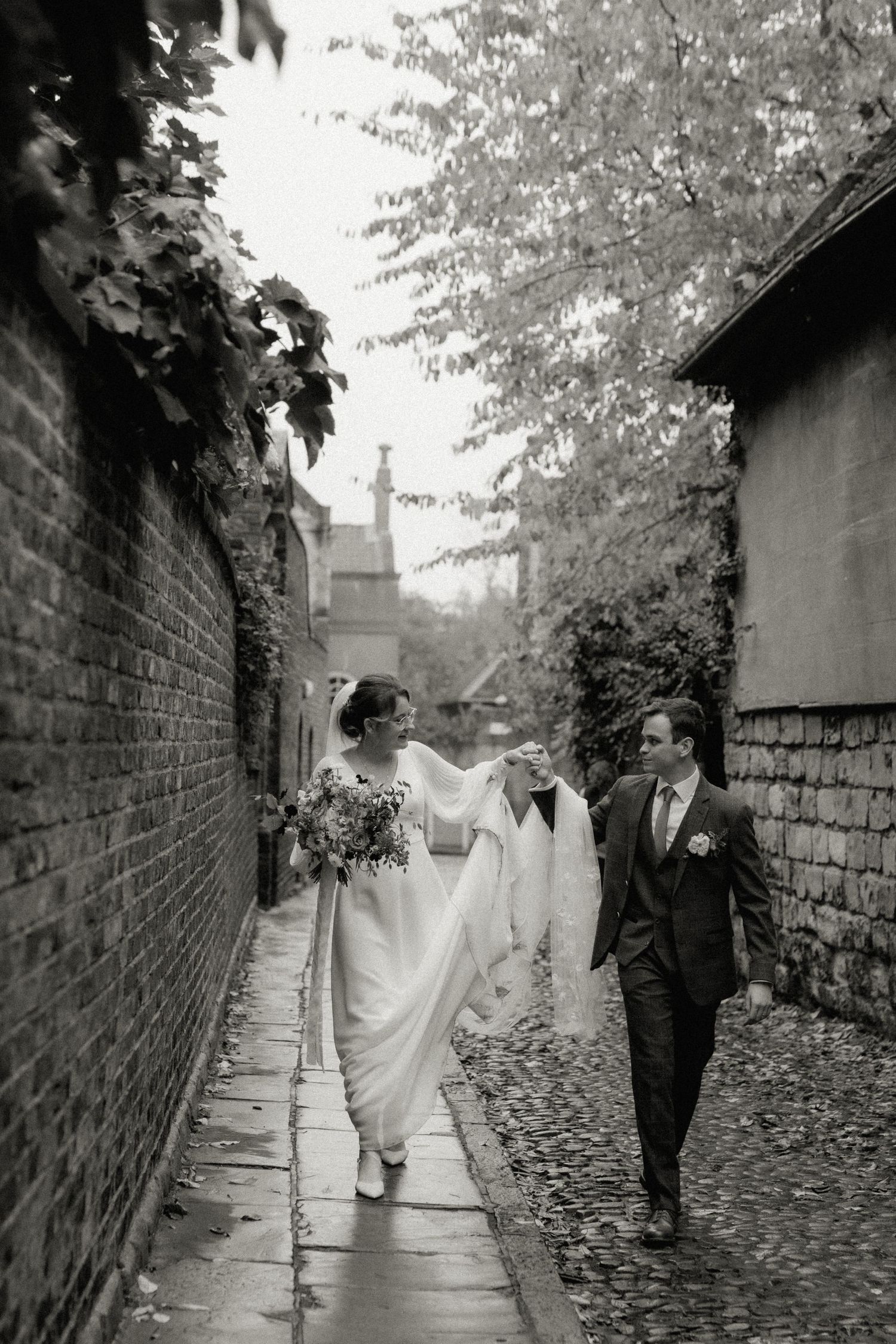 A romantic black and white photo of a couple walking along a cobblestone alley in York. York Wedding.