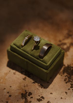 A close-up sequence of a diamond engagement ring in a green velvet ring box.