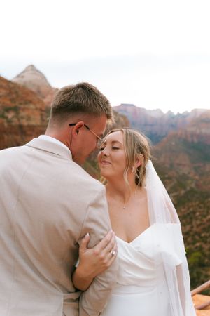 A romantic moment captured between newlyweds against a backdrop of majestic desert cliffs.