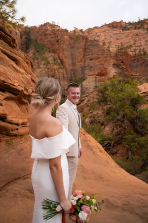 Newlyweds share an intimate moment while walking along scenic desert cliff paths.