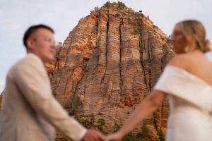 A couple embraces during their wedding photoshoot with towering red rock formations in the background.