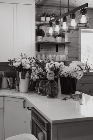 Modern kitchen counter displaying various white floral arrangements and vases.