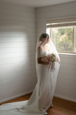Empty white room with wooden floors and windows draped in sheer curtains.