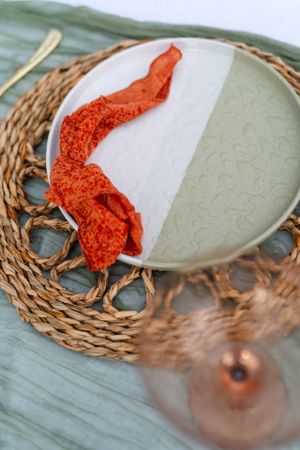 Orange and white decorative plate on a woven rattan charger with soft lighting.
