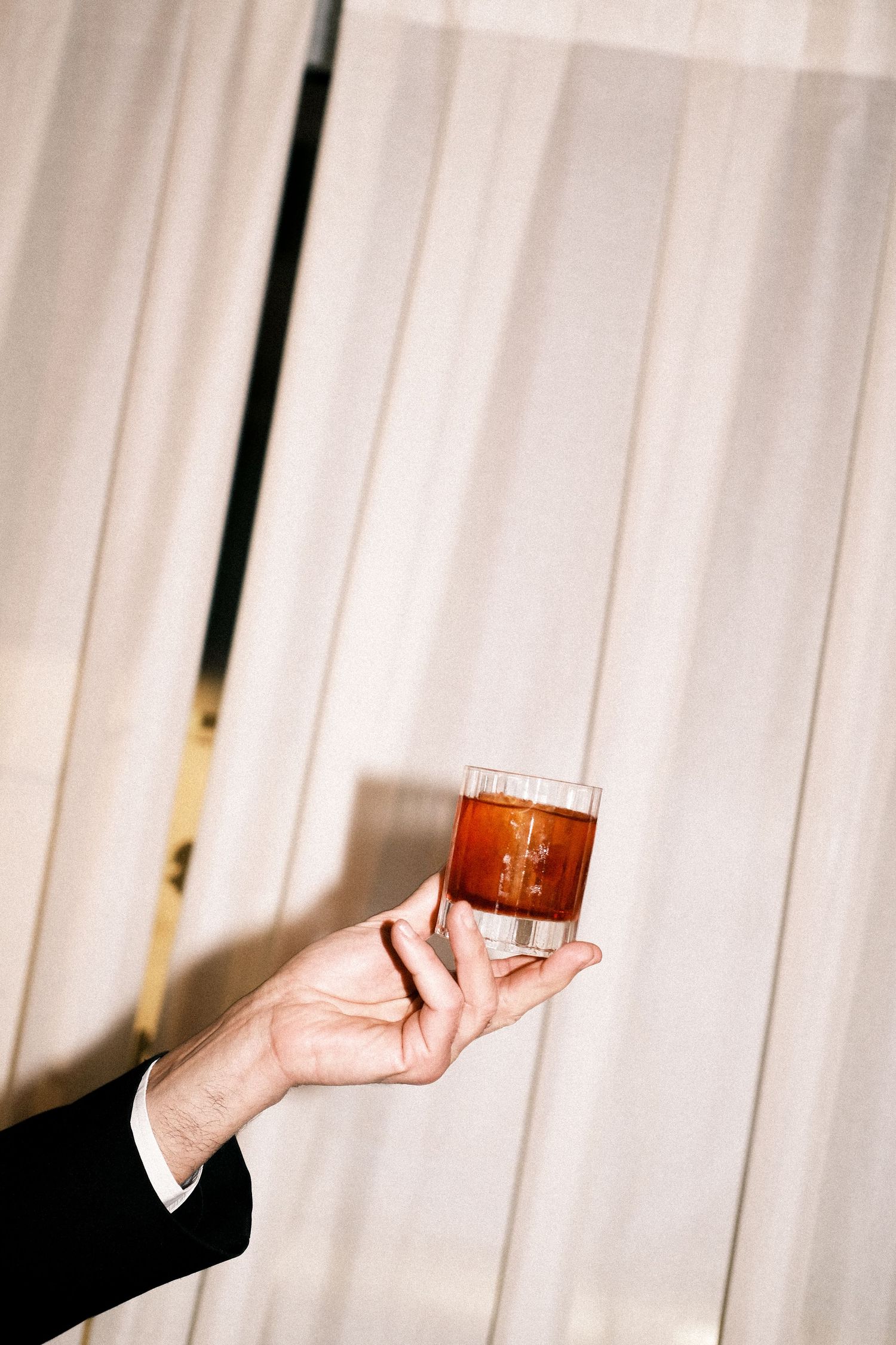 person holding a Negroni cocktail in a rocks or old-fashioned glass