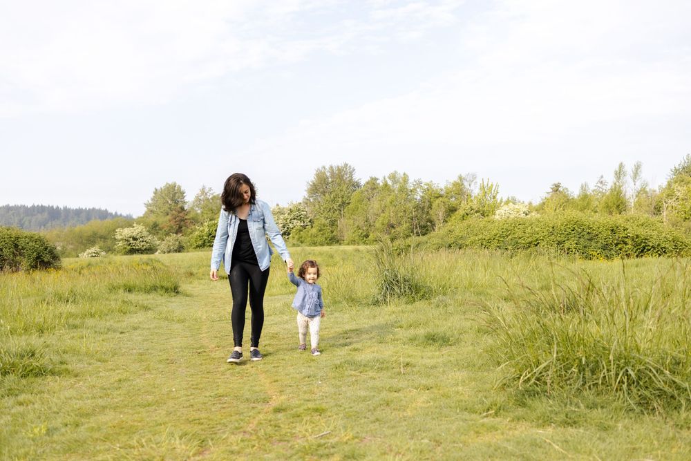A couple walks hand in hand through a lush green meadow on a sunny summer afternoon.