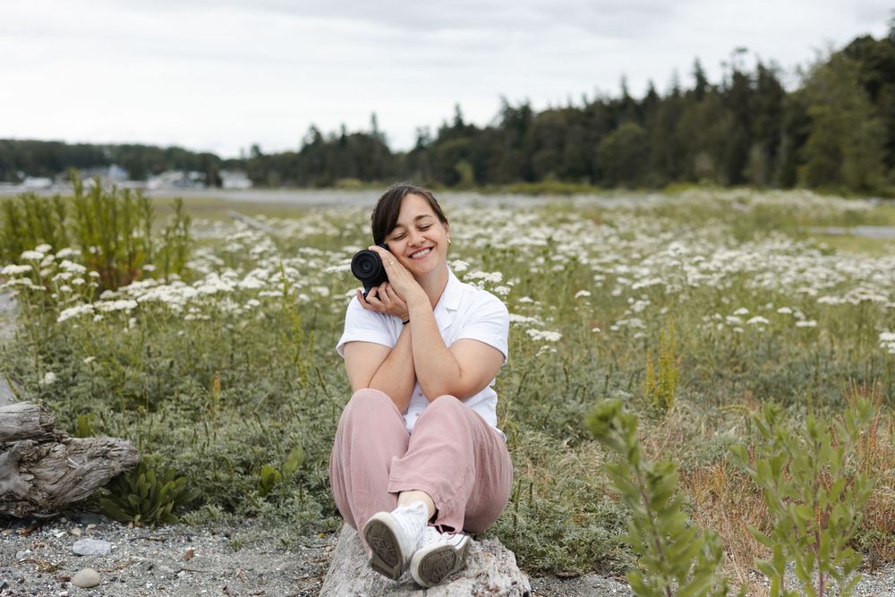 Someone poses playfully in a blooming wildflower meadow on a sunny summer day.