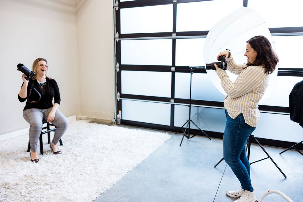 Professional photographer capturing lifestyle portraits in a bright studio with natural window light.