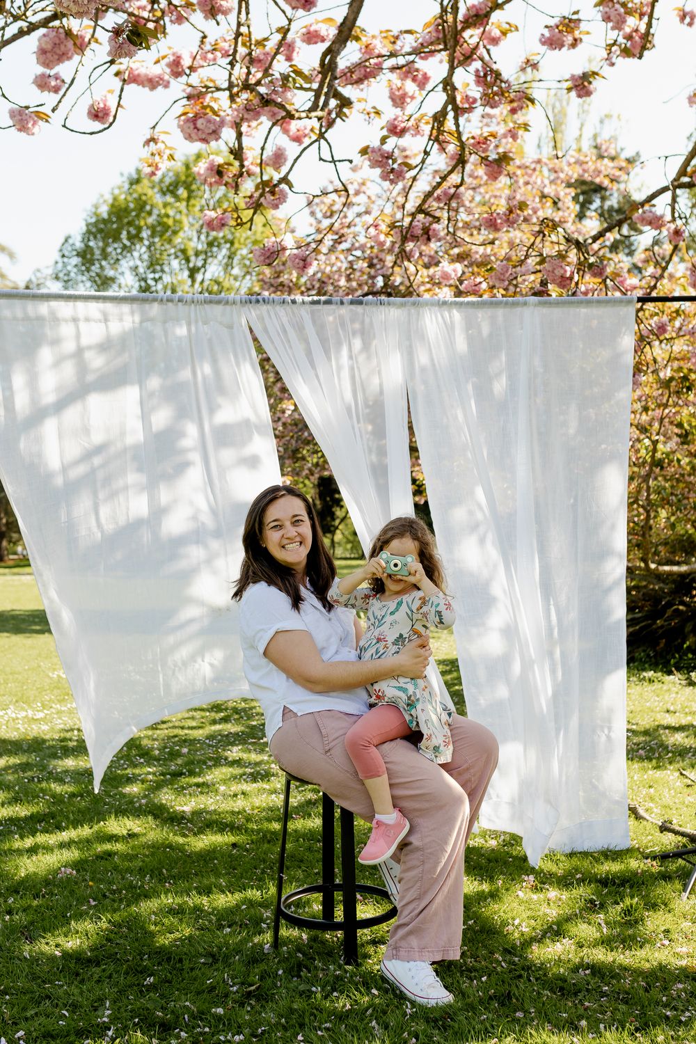 A playful scene of laundry hanging on clotheslines outdoors with pink cherry blossoms blooming in the background.