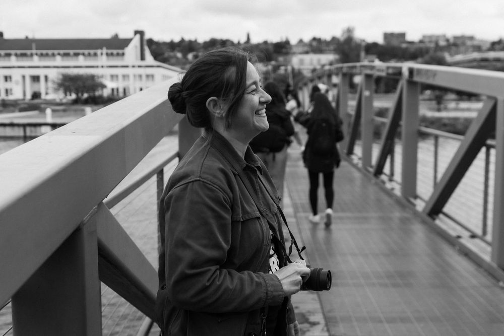 A black and white panoramic collage shows people walking along what appears to be a bridge or elevated walkway.